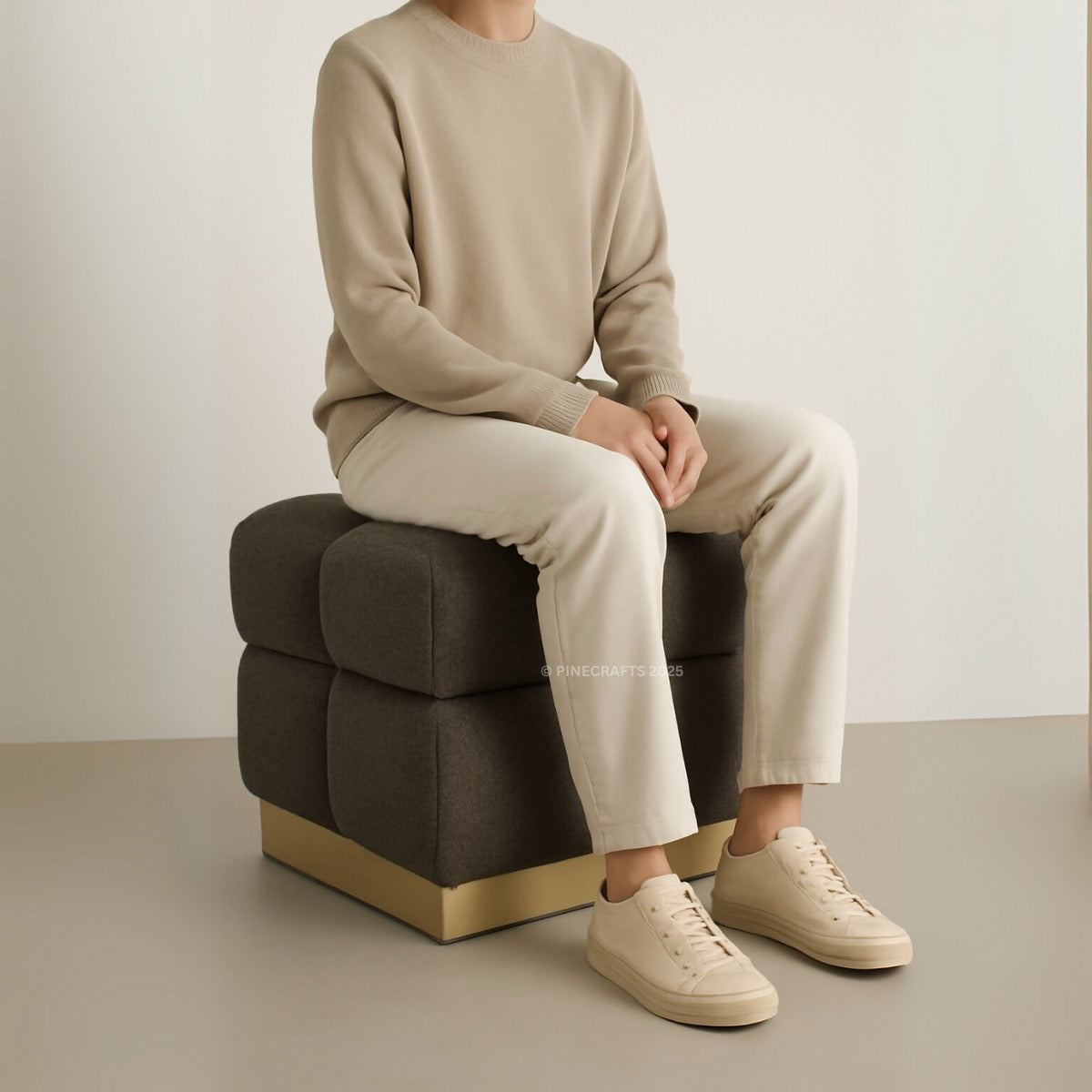 Person sitting on a modern brown ottoman with a neutral background